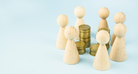 Business concept. Wooden figures of people stand around coins on a blue background. Teamwork. Earning money. Business ideas, business success. Business recovery and growth. Copy space.