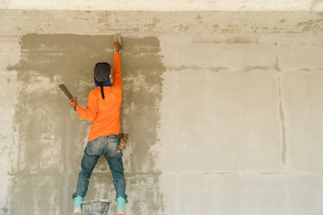 Construction worker plastering the walls of the room. Plastering the walls is a job that requires the skill of a technician.