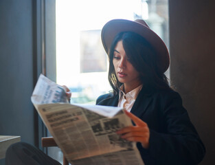 Fototapeta na wymiar Young asian lady, in classic business suit and hat with newspaper in cafe, retro character style