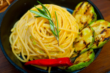 italian spaghetti pasta with zucchini sauce on iron skillet