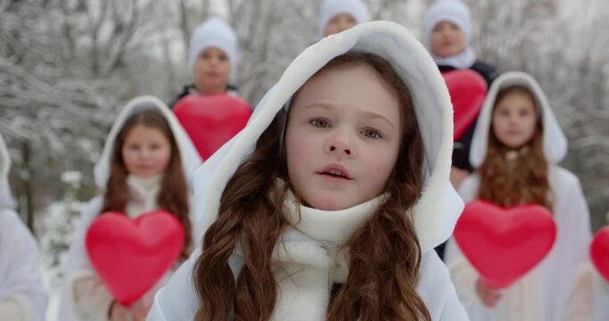 A group of children sing a song in a snowy park