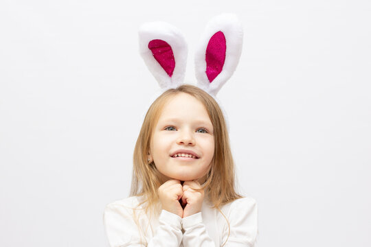 Portrait of happy little smiling girl with bunny ears isolated on white background.