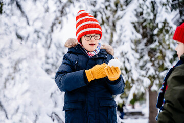 Making snowball and winter fun for children. Enjoying nature wintertime. Winter emotion. Winter children happy. Joyful little boy with down syndrome child Having Fun in Winter Park. © Iryna
