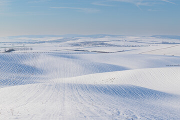 Winter snowy rolling landscape in the Czech Republic - in Europe. Blue sky with white clouds.