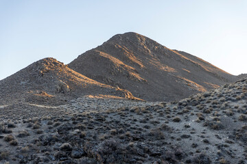 Streaks of light touch the mountains as the sun goes down in the desert