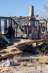 Fototapeta na wymiar Burned walls and a brick chimney fallen timbers and belongings on the ground after a fire