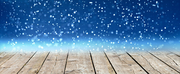 Wooden board or plank as a copy space with digitally generated snowfall in night winter season background. For Christmas day and New Year concept