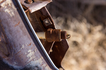 Rust covered spark plug rests on a piece of old car engine