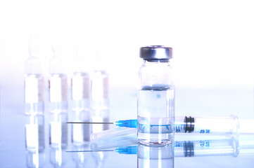 syringe and diferent kind of ampoules and vials close-up on white background with reflection