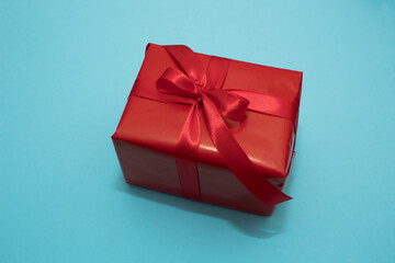 Red box with red ribbon on a blue paper background. Valentine's Day gift