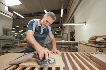 Serious craftsman working at modern furniture manufacture
