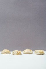 Manty with meat, tomatoes, herbs, sauce and pepper peas on grey minimalistic