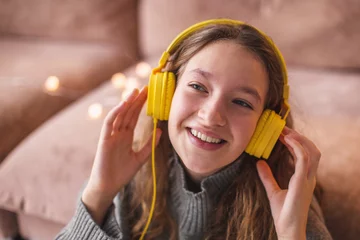 Poster een girl in modern headphones sit relax on floor near couch listening to music, © Tatyana Gladskih