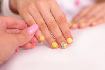 Obraz na płótnie Canvas Little girl hands with beautiful manicure nails, yellow gel polish, flower design