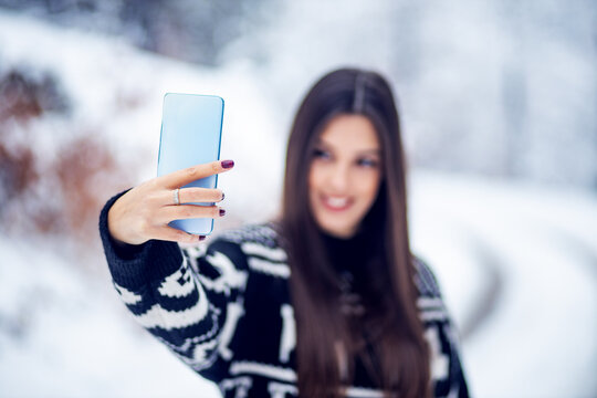 Beautiful woman take a selfie with his smartphone at winter outside
