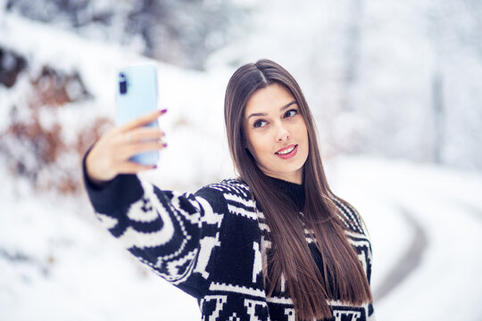 Beautiful woman take a selfie with his smartphone at winter outside