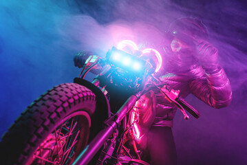 A futuristic motorbiker on the neon light motorcycle close up.