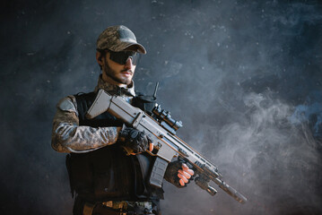 Futuristic soldier with a rifle on the black smoky background.