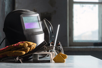 Welding helmet on the metal workbench background.