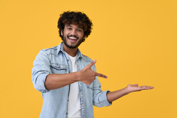 Excited happy positive young indian man student pointing aside with fingers hand gesture at copy...