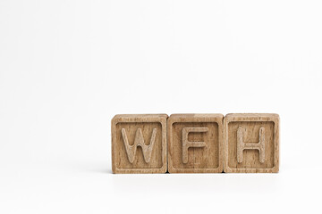 WFH (work from home) theme. wooden cubes with the acronym WFH, on white background. photo with space for text