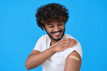 Happy young adult indian latino man showing bandage plaster on arm after getting vaccination...