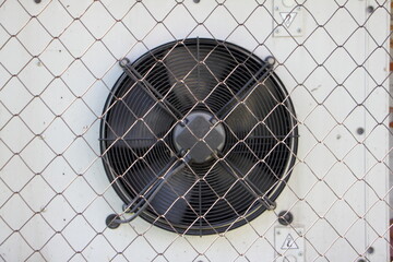 Industrial air conditioner outdoor unit with cooler fan behind a metal net 