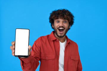 Excited young indian man holding cellphone showing big white blank empty mockup screen. Surprised...
