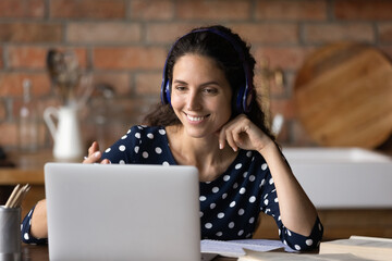 Happy millennial latin woman in headphones holding video call conversation, talking communicating...
