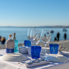 Verres et assiettes sur une table de restaurant sur une plage de galets à Nice sur la Côte d'Azur...