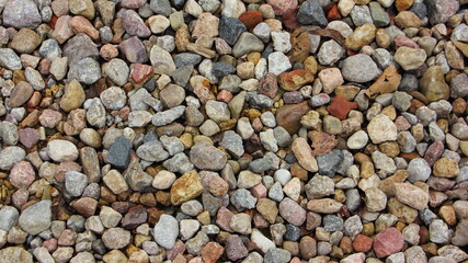 A lot small colored dry stones close up on gravel beach background texture