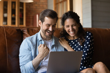 Cheerful bonding millennial family couple celebrating internet success, looking at laptop screen, getting online lottery gambling auction betting giveaway win notification, last birds trip purchase.