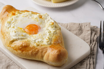 Traditional georgian dish of cheese-filled bread adjarian khachapuri with fried egg on a marble board