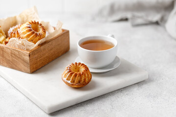 Cup of tea with muffins in wooden box on white board and table