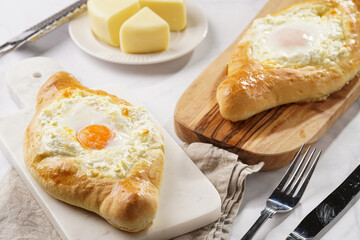 Traditional georgian dish of cheese-filled bread adjarian khachapuri with fried egg on a marble board