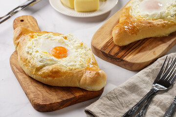 Traditional georgian dish of cheese-filled bread adjarian khachapuri with fried egg on a wooden board