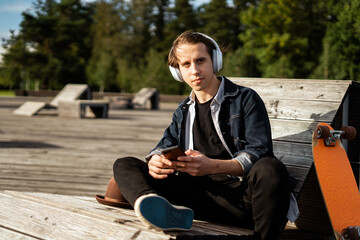 Skateboarding in the city and surfing in the phone music headphones. Milinal is a young man in a hat and a denim jacket.