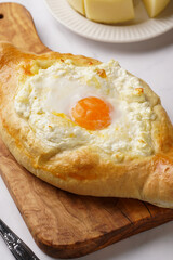 Traditional georgian dish of cheese-filled bread adjarian khachapuri with fried egg on a wooden board