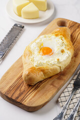 Traditional georgian dish of cheese-filled bread adjarian khachapuri with fried egg on a wooden board