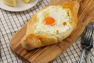 Traditional georgian dish of cheese-filled bread adjarian khachapuri with fried egg on a wooden board