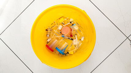 Waste bin with used syringes, vials, test containers, on the tile floor. Top View
