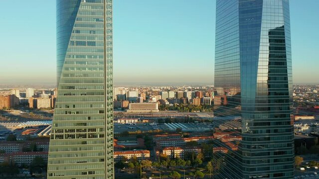 Forwards fly between two modern office towers. Revealing large logistic site and train station. Town development at golden hour.
