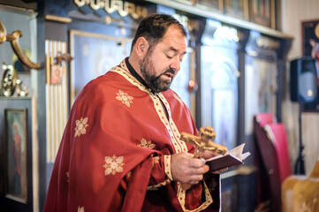 Religious priest holds holy Christian cross during religious chuch ceremony