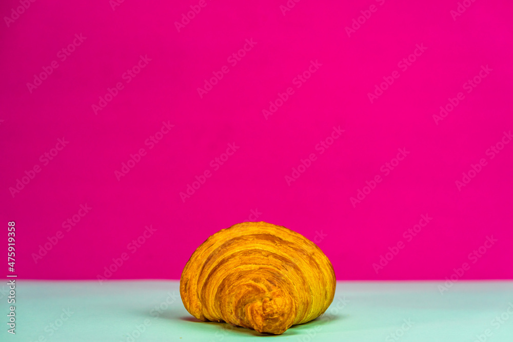 Sticker closeup shot of a tasty croissant on a gray surface and pink background