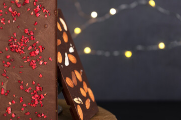 Natural organic milk and bitter chocolate bars with sublimated berries and almond with black background. Confectionery ingredients.