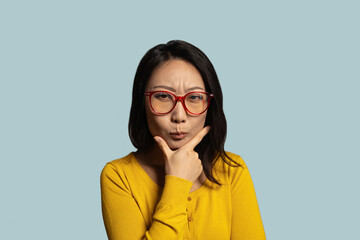 Thoughtful asian woman look away holding hand on chin. girl student or freelancer in eyeglasses...