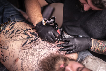 Professional tattooist making a tattoo in tattoo studio