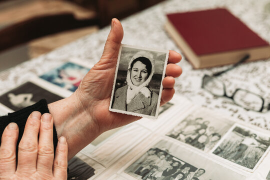 Elderly woman hands holding a photo of the young woman. Passing of time concept