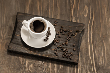 Cup with espresso coffee and coffee beans on a wooden table. Copy space