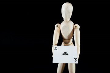 Human wooden dummy holding a cross ace card, isolated on black